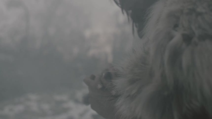 A man wearing a fur coat clasps and rubs his hands together in a snowy setting