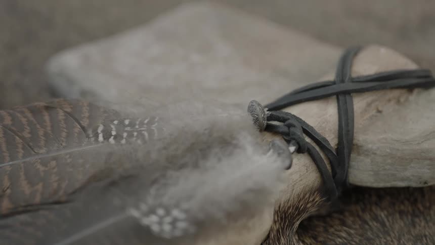 An ax with feathers tied on by a cord rests on fur