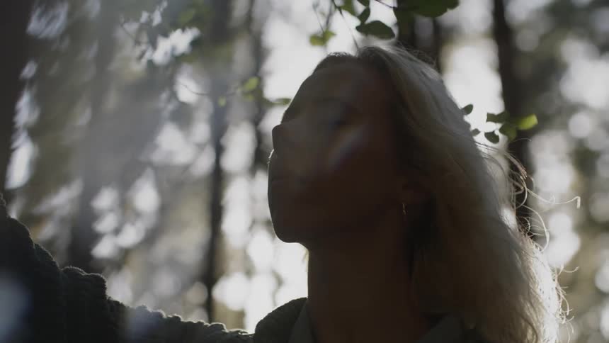 A woman stands in the windy forest