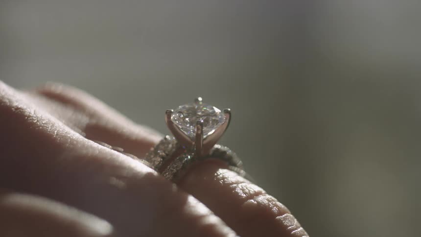Large diamond in ring on finger sparkles in the sunlight