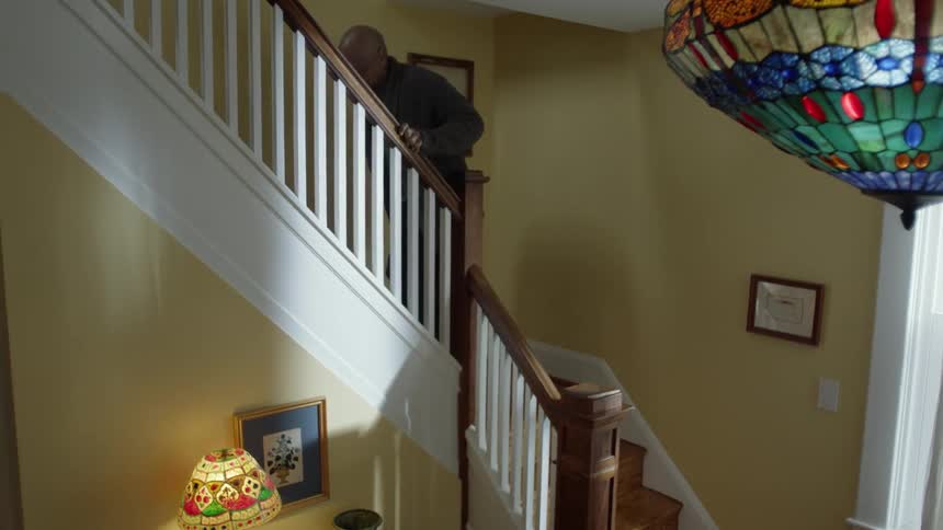 Elderly man climbs staircase in home slowly