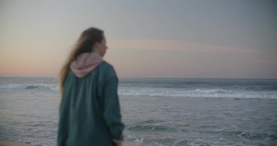 A woman is walking on the windy beach