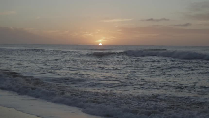 The sun is rising on the beach