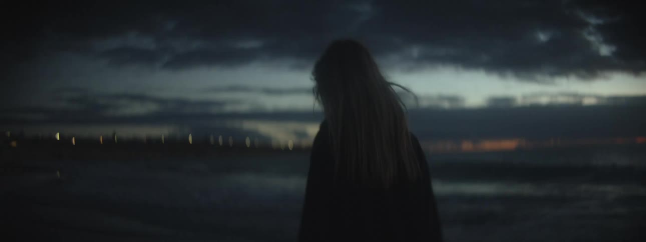 Silhouette of a woman walking along the beach next to the ocean at sunset
