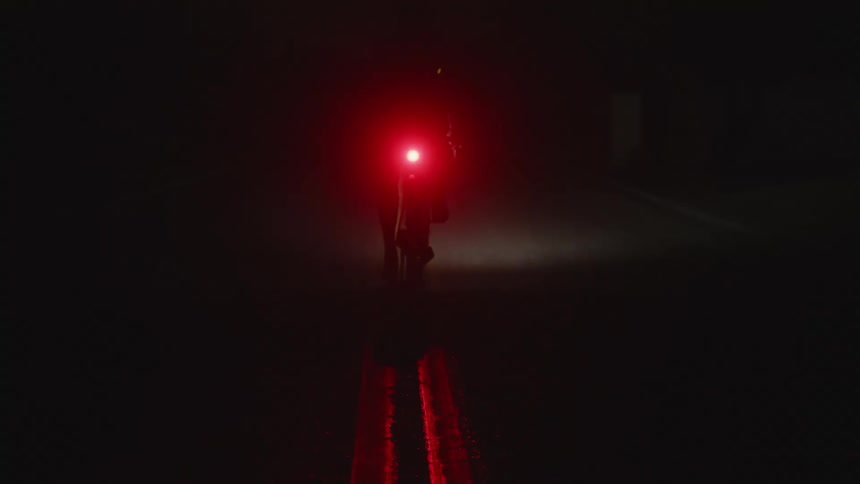 A person rides their bike on the road at night