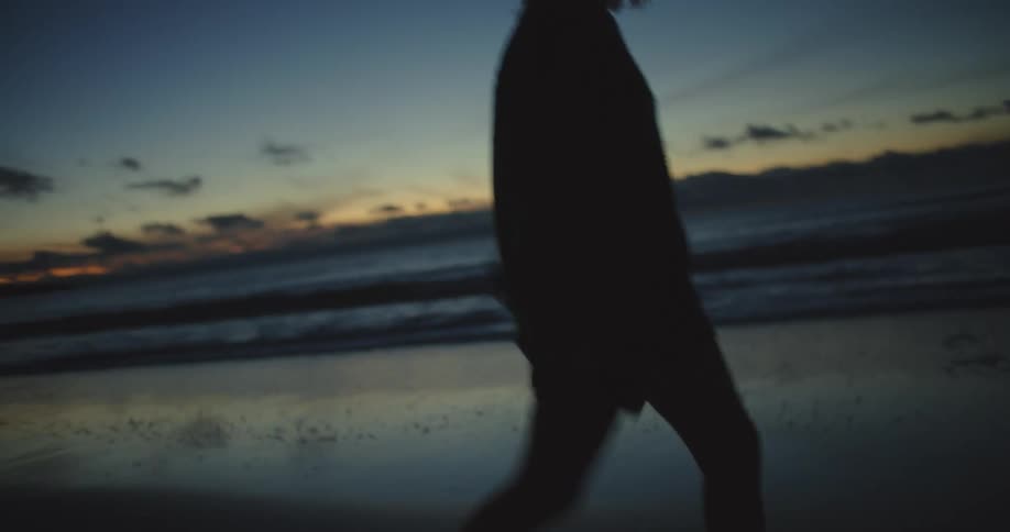Two women walk on the beach at sunset