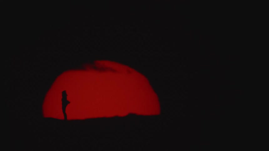 A woman spins in front of the setting sun