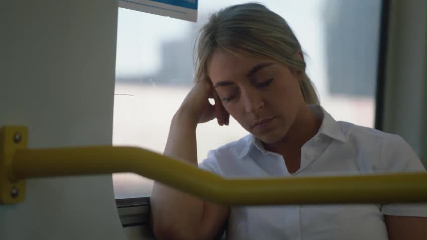Female passenger sleeps while riding on public transport passing through city