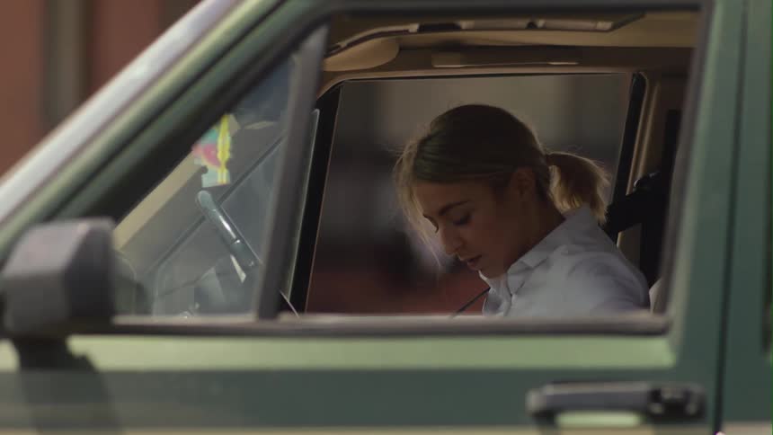 A woman is driving in a car during spring