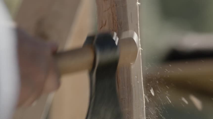 A person cuts wood with a small hatchet