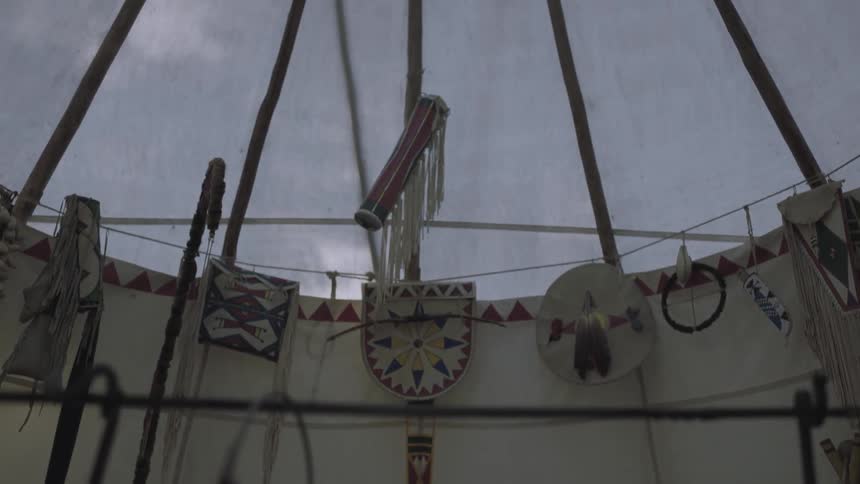 There is a fire burning under a bucket inside of a teepee