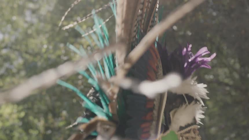 Person wearing a large colorful headdress while dancing