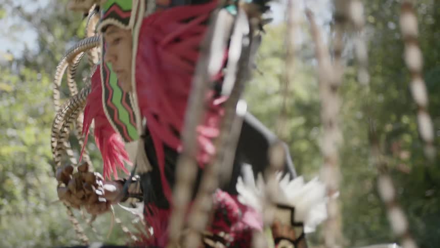 Man wearing elaborate headpiece does a ceremonial dance