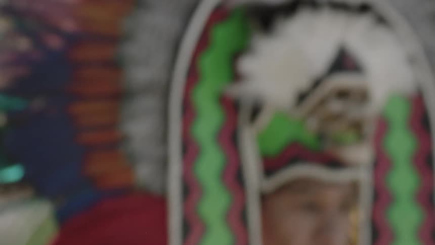 A man wearing a large, feathered headdress while performing a traditional dance