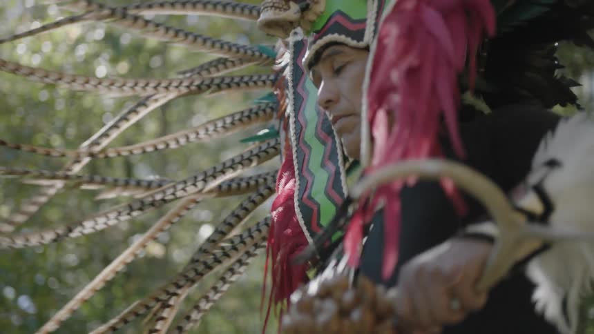 Tribal man with a full headdress dancing in the forest