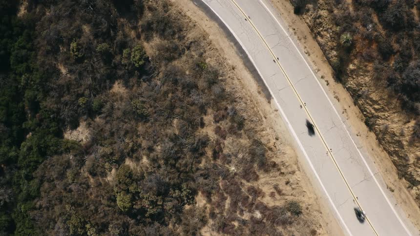 Aerial view of two motorcycles traveling on a road surrounded by rocks and plants