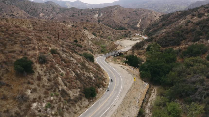 Two motorcycles are traveling on a winding mountain road
