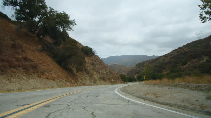 A curving rural highway heading towards the mountains on a cloudy day