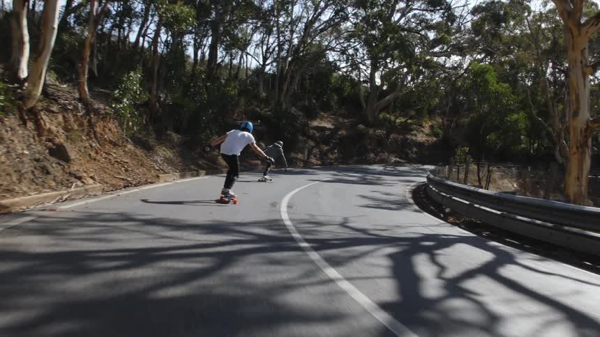 Two people are skateboarding in a rural area