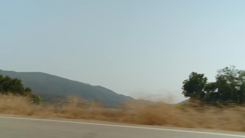 Two people drive motorcycles along the shore