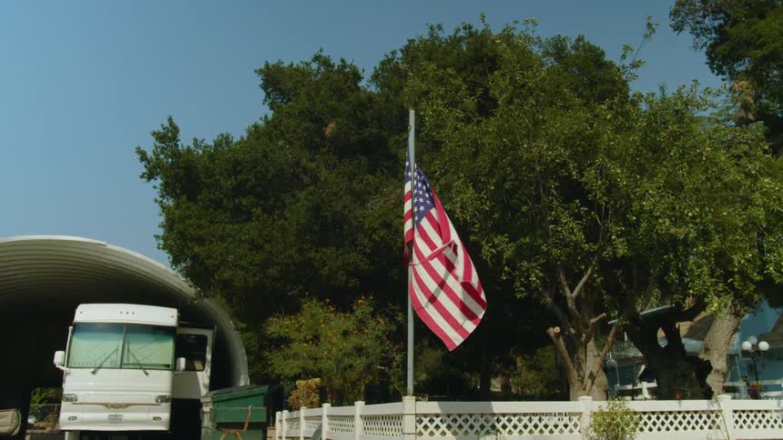 Torn american flag waving on a flagpole in a neighborhood at daytime