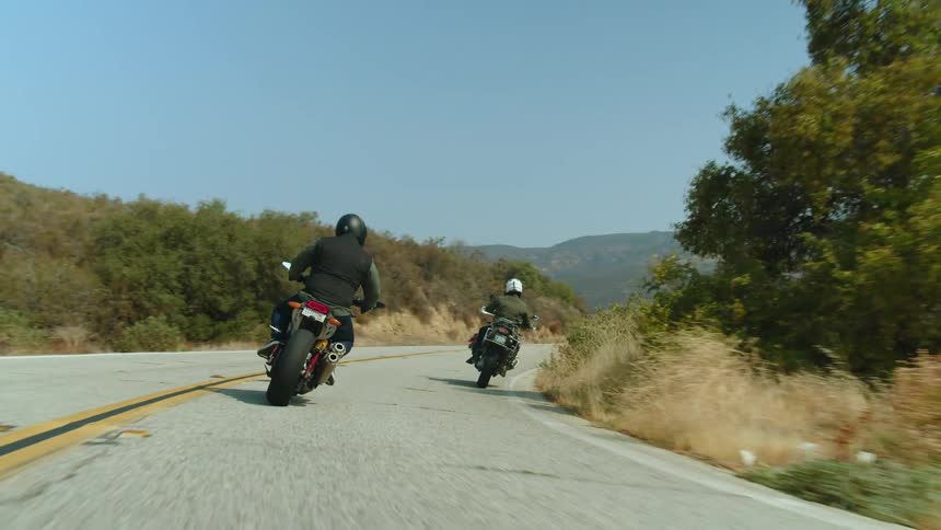 Motorcyclists ride down a curve on a highway