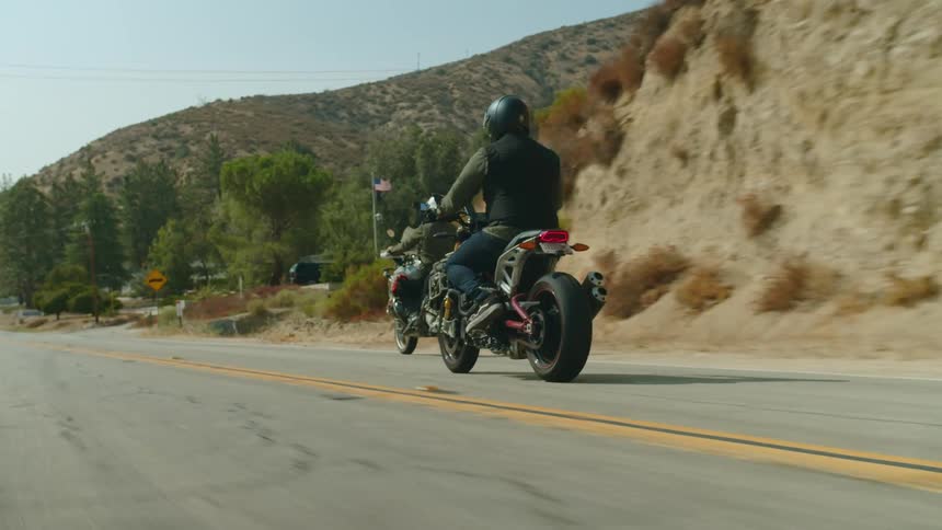 Two men ride motorcycles along a mountain highway