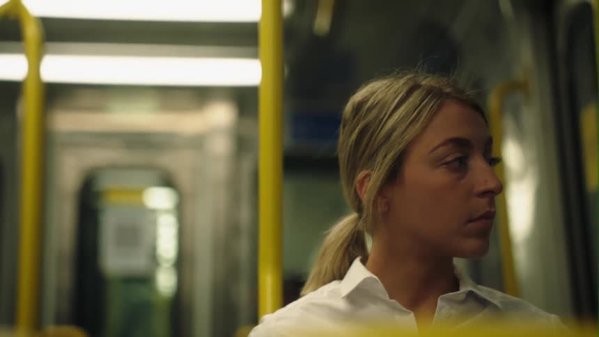 A woman is sitting on a train looking out the window as it travels