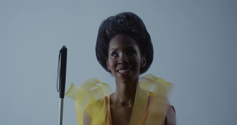 A woman wearing a yellow outfit is standing outside smiling as she holds a rod with a handle