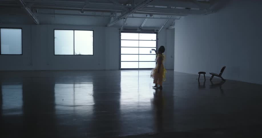 A dancer takes several steps forward and raises her arm