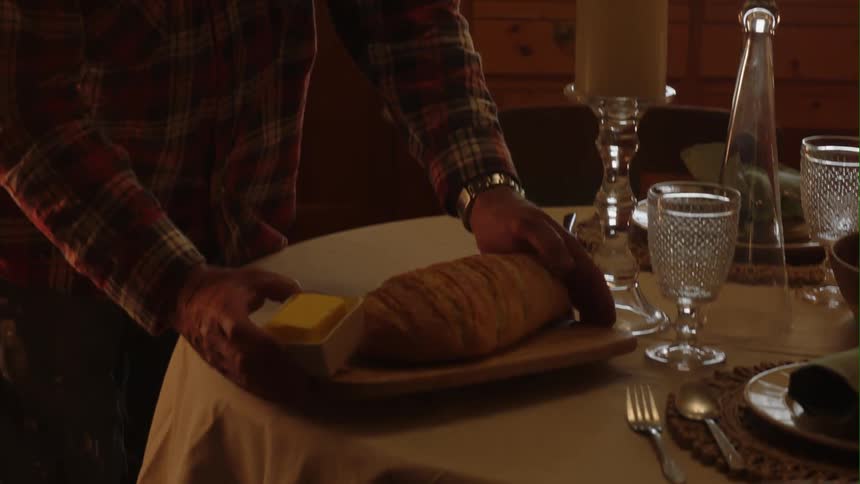 A man at home sets some bread and butter on a table