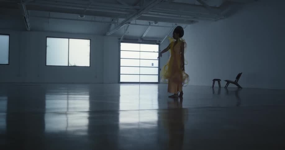 A woman starts performing a modern dance in a dance studio