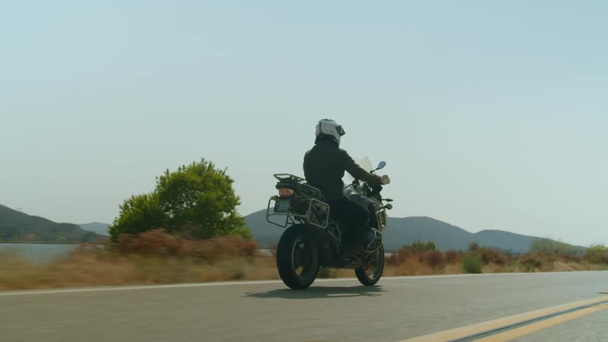 A person is driving a motorcycle in a rural area