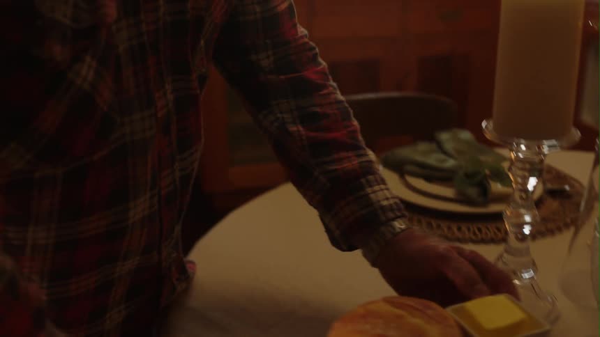 A man places a loaf on bread on a table for dinner