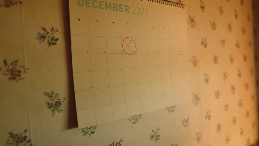 Person wearing plaid circles already marked date on wall calendar