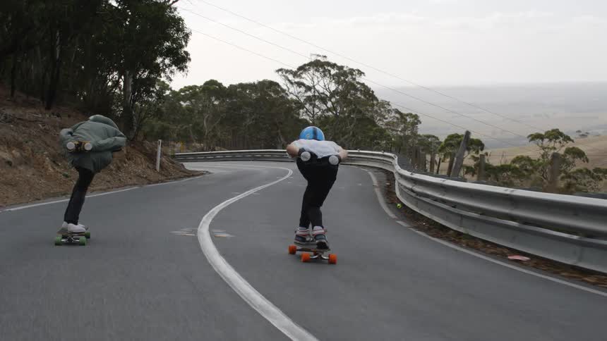 Two people are skateboarding on a highway