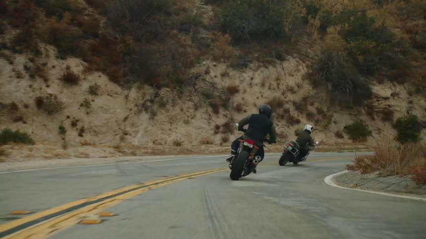 Two people ride motorcycles on the road
