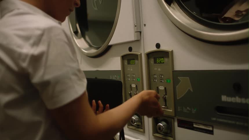 A woman puts coins in the washing machine