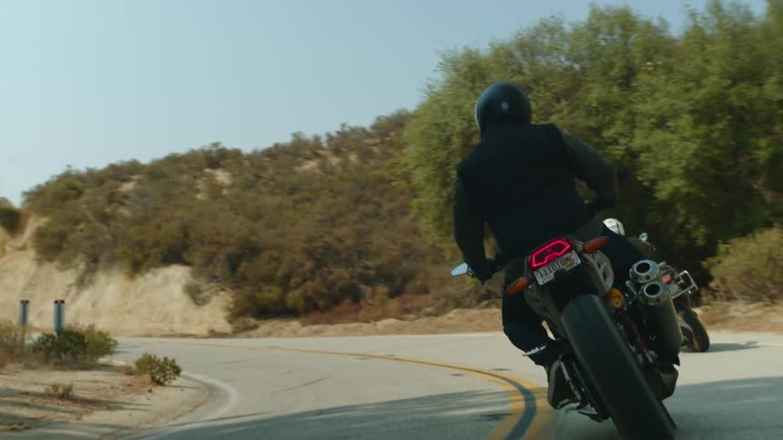 Two motorcyclists ride sideways down a curve in the road