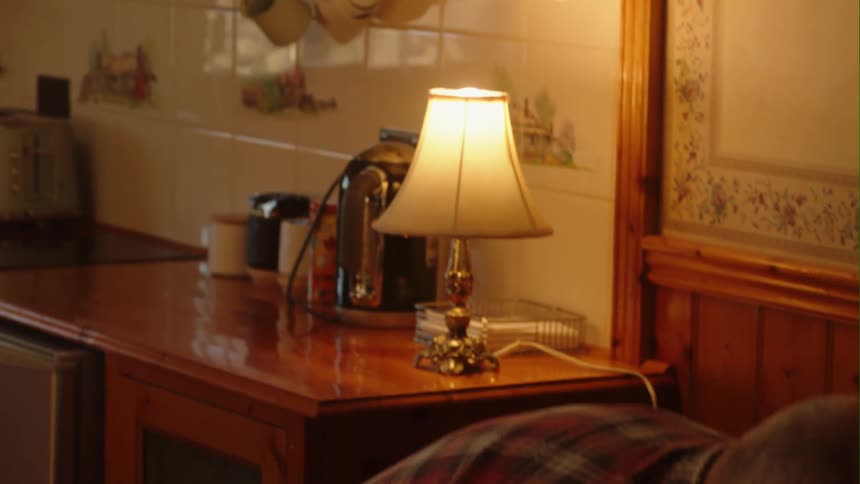 Man with red plaid shirt and jeans lays table in the kitchen