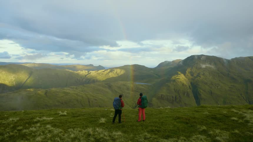 Two men out hiking in the hills stope and look at the landscape