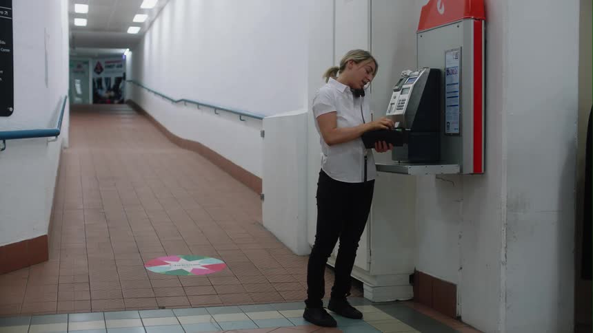 A woman uses a pay phone to call someone and talk