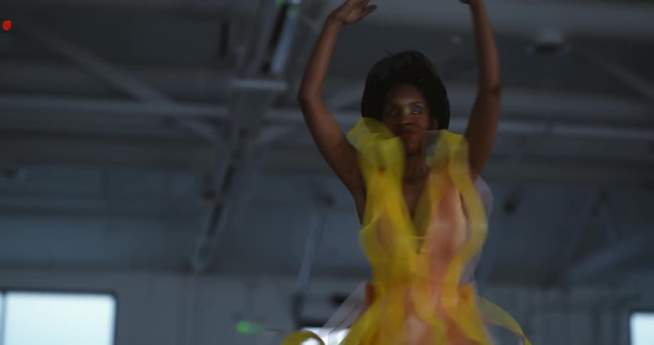 A woman in a costume and makeup dances in an industrial space