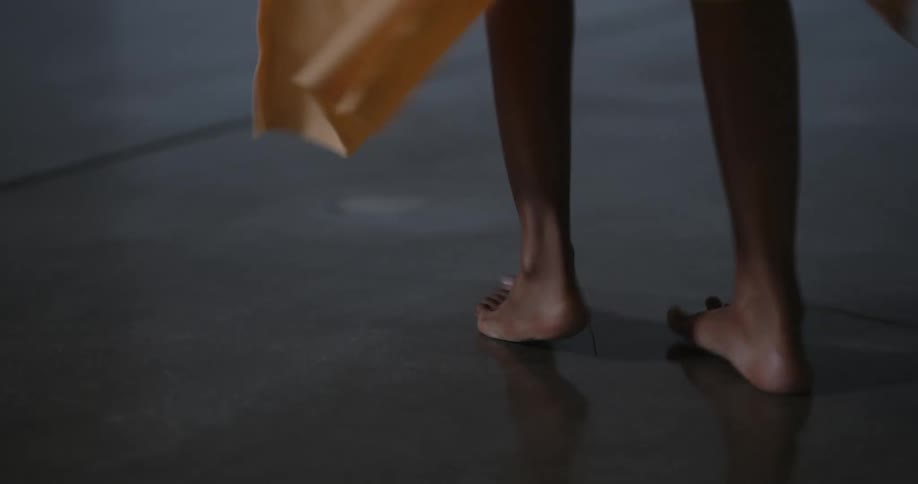 Female dancer dances barefoot on smooth slightly reflective floor