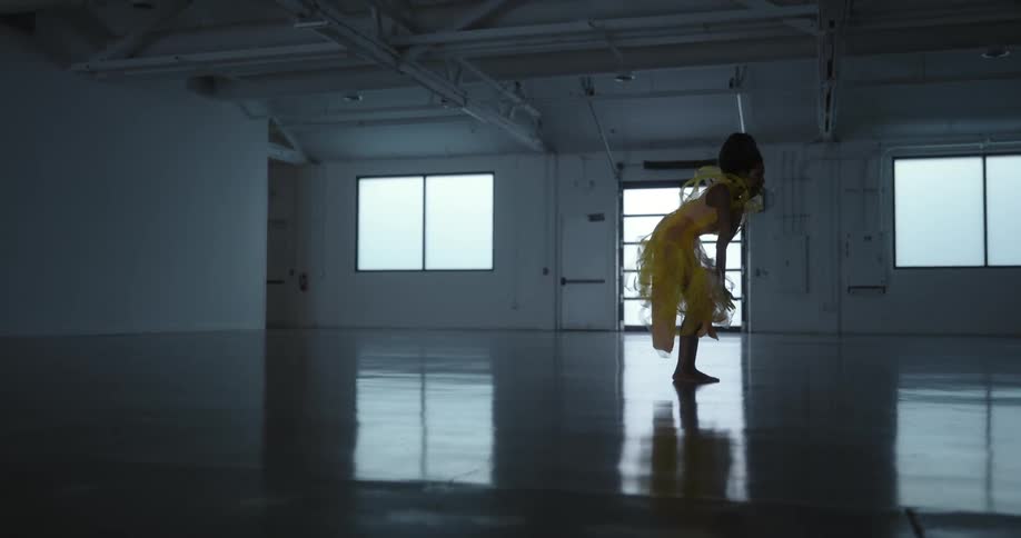 Female model with frizzy hair makeup with glitters and yellow dress dances in studio