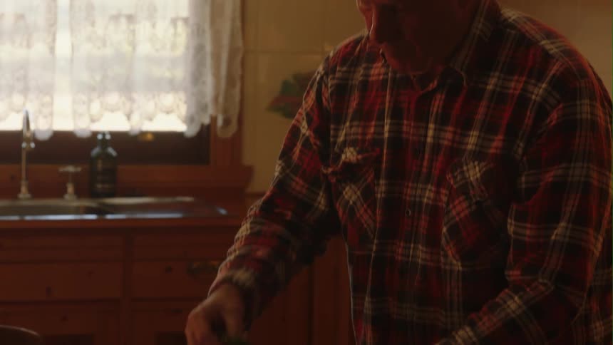 Man with plaid shirt lays the table in the kitchen