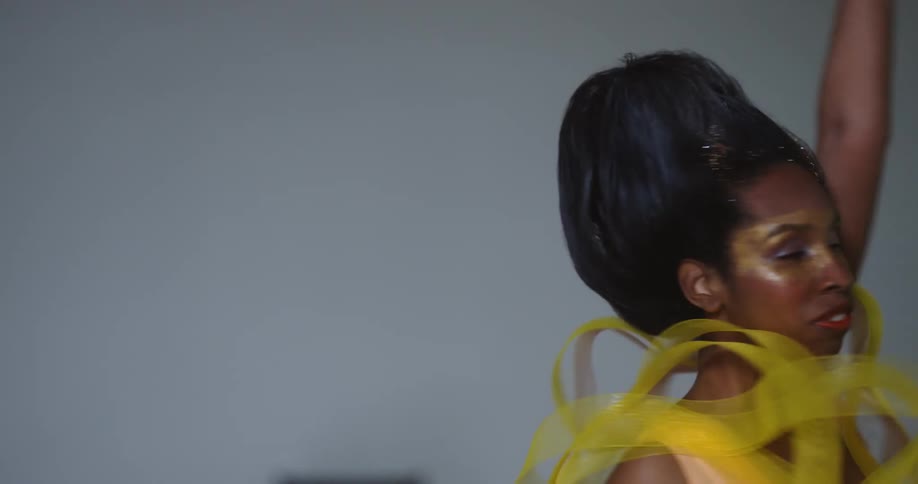 A woman is wearing a dress and dancing in a room