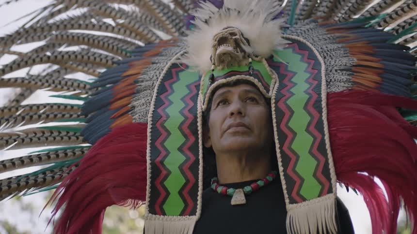 An elaborate native american headpiece is worn by a man