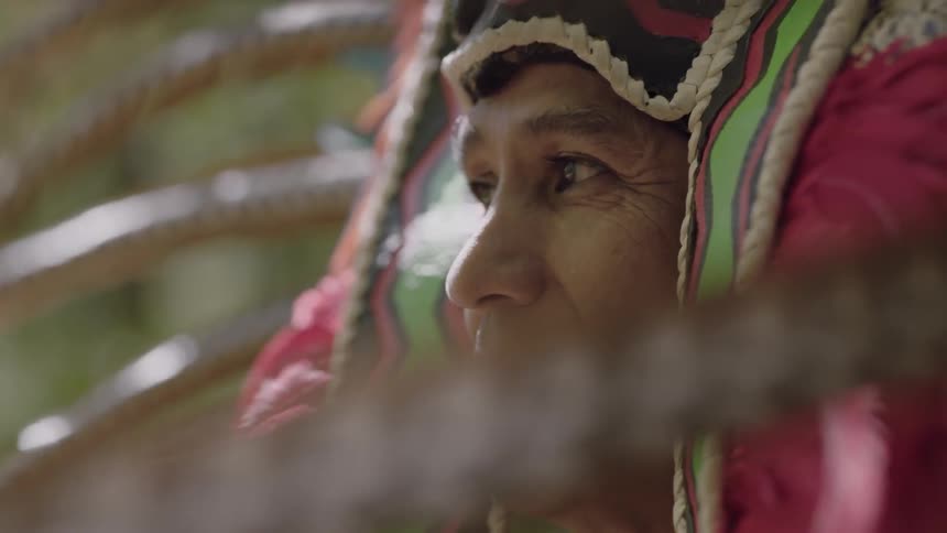 A native american man wearing a ceremonial headdress looks around at his surroundings