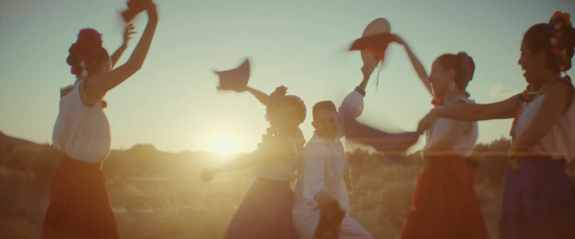 A group of friends in cultural costume dancing and laughing as the sun shines on them in the desert